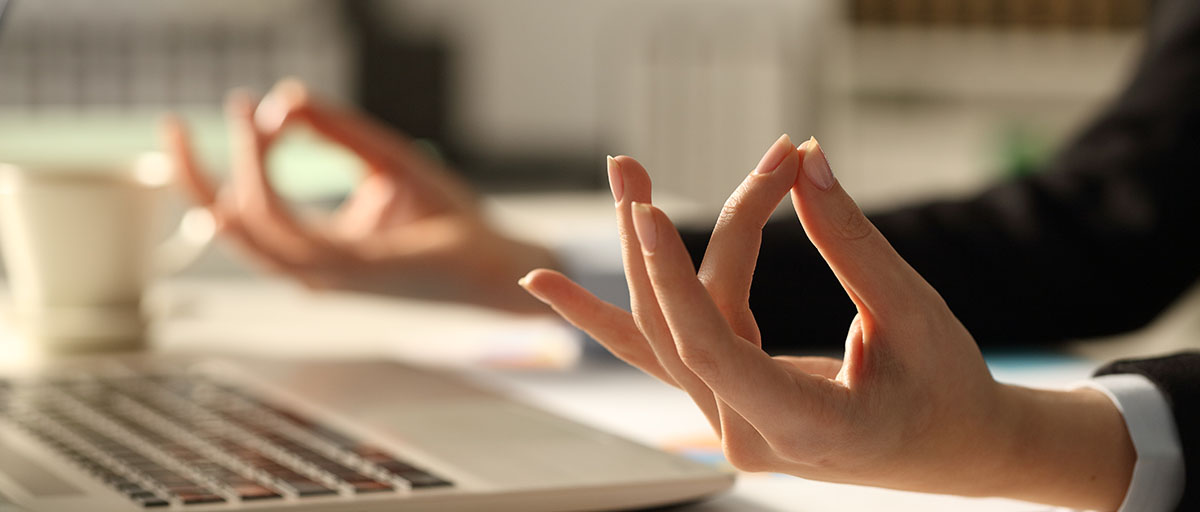 Ofiste, masa başında meditasyon yapan bir çalışanın ellerine yakın çekim.